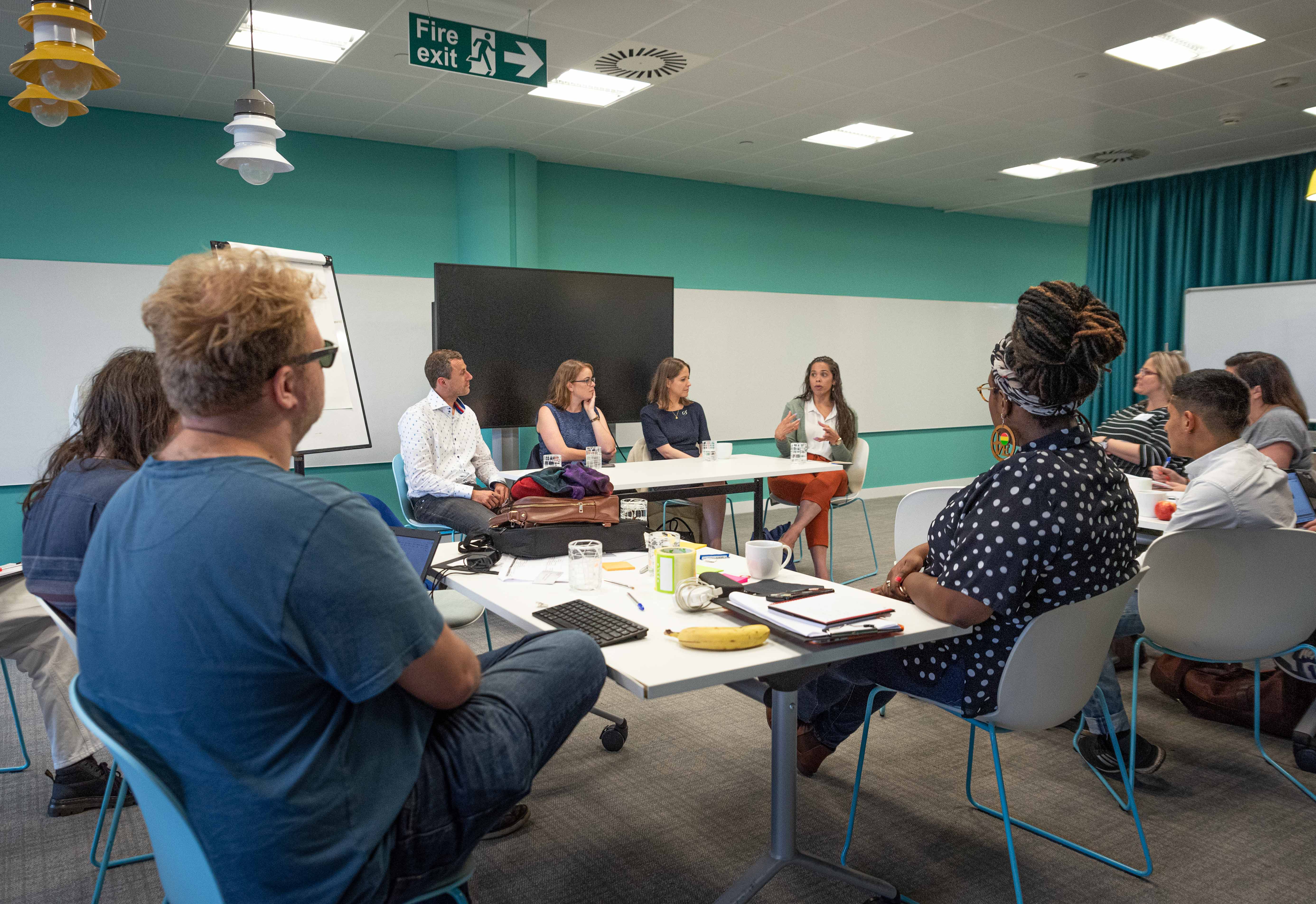 People round desks in a group setting